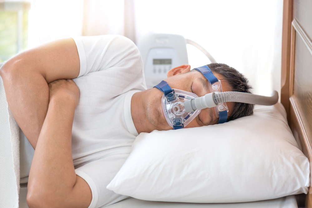 Happy and healthy senior man wearing Cpap mask sleeping smoothly all night long on his left side cross arms without snoring.Obstructive sleep apnea therapy.

