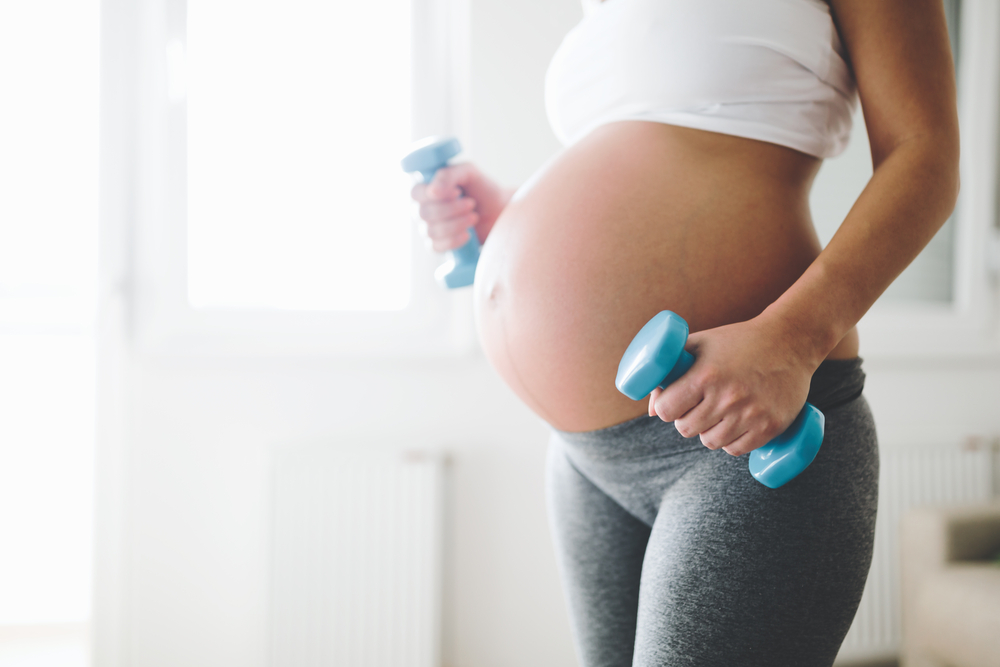 Sporty pregnant woman exercising with dumbbells