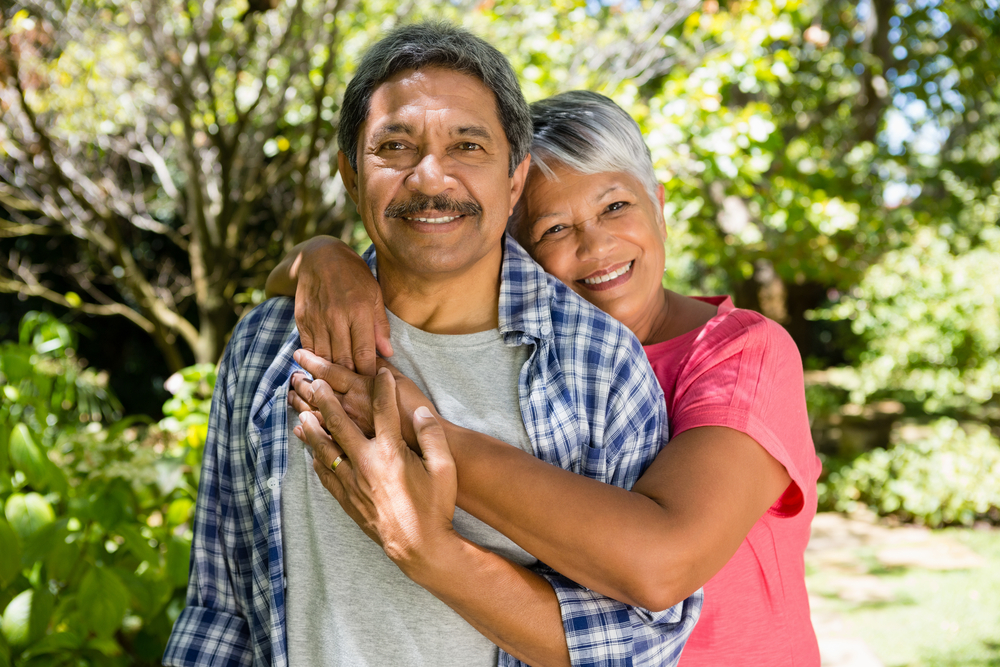 Portrait of senior couple embracing each other in garden on a sunny day
