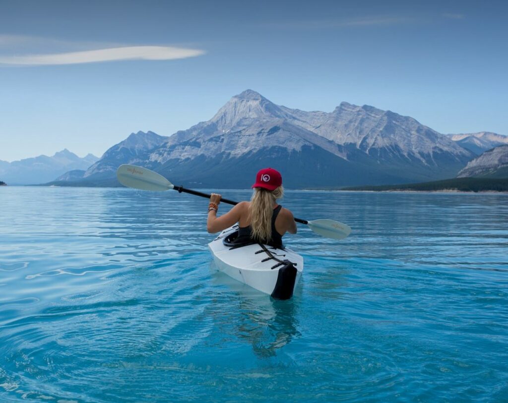 Woman kayaking. Mountain and water in the background. 