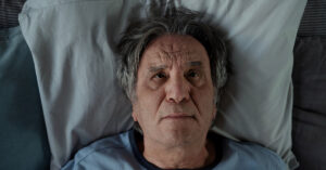 man laying in bed with head on pillow seen from above