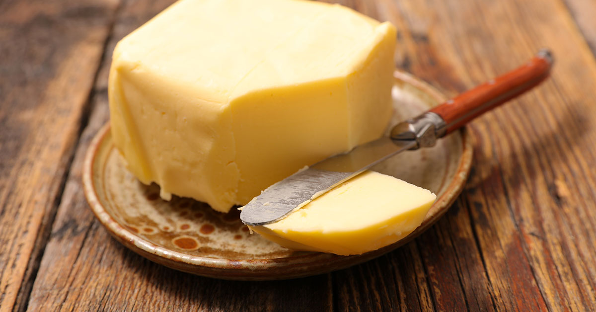 Butter on plate with knife cutting off a small slice