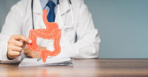 A Major Cause of Inflammatory Bowel Disease (IBD) Has Been Discovered doctor holding 2d model of stomach and large intestine