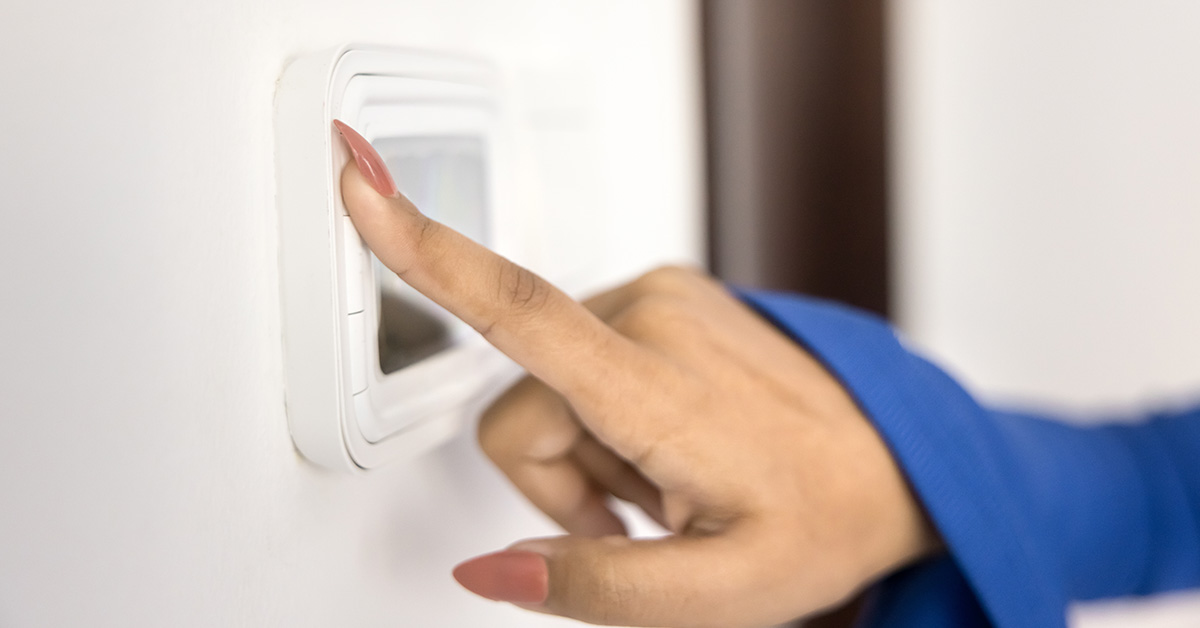 person's hand adjusting AC from thermostat in home