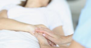 Woman Dies by Euthanasia Just Days After 29th Birthday Medical staff holding the hand of woman laying in hospital bed