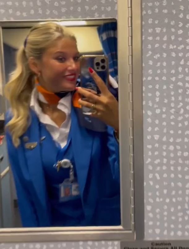A flight attendant posing in front of a mirror