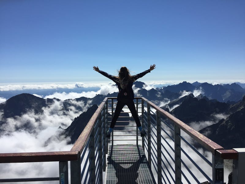 Person standing on rails with arms wide on a mountian
