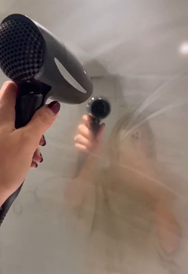A fogged mirror being defogged by a hair dryer. 