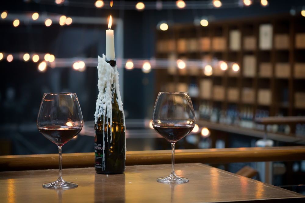 Two glasses of red wine on a table with a candle in a wine bottle. Setup in a bar in Edinburgh, Scotland