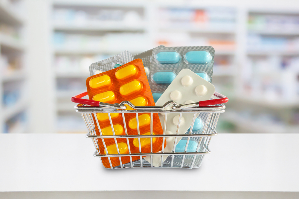 Medicine pills package in shopping basket with pharmacy drugstore shelves blur background