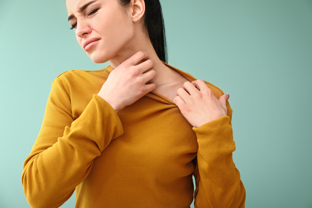 Young woman with skin allergy on color background