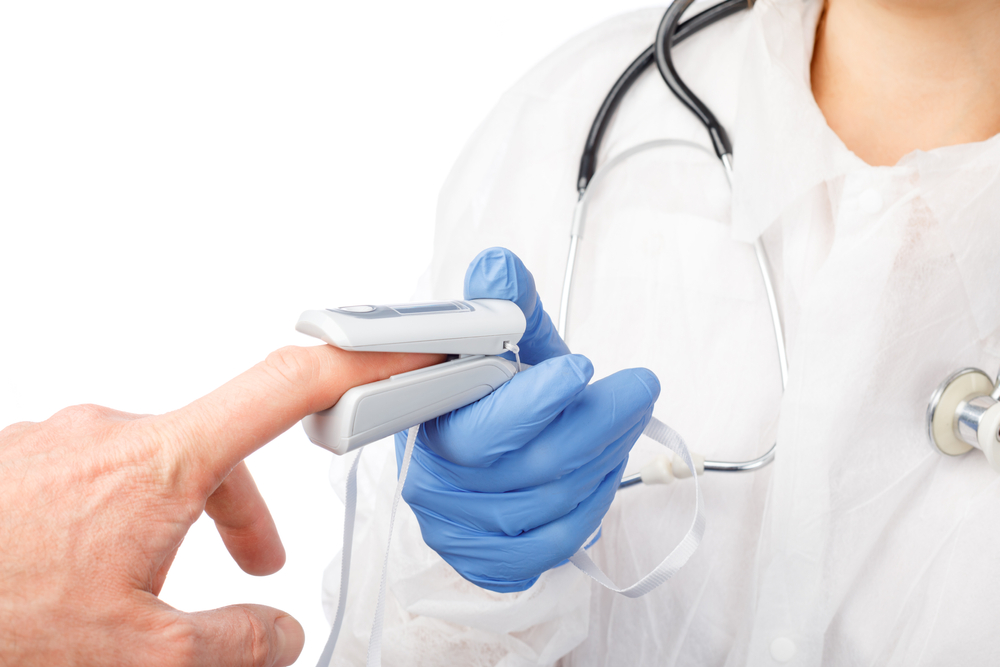 Close-up shot of doctor using finger pulse oximeter to check oxygen saturation and heart rate of a person tracking coronavirus symptoms - epidemic virus outbreak concept