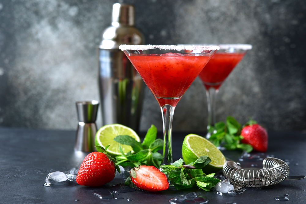Cold summer strawberry cocktail with lime and mint ( mojito, margarita, rossini,daiquiri ) in a martini glasses on a dark slate, stone or concrete background..
