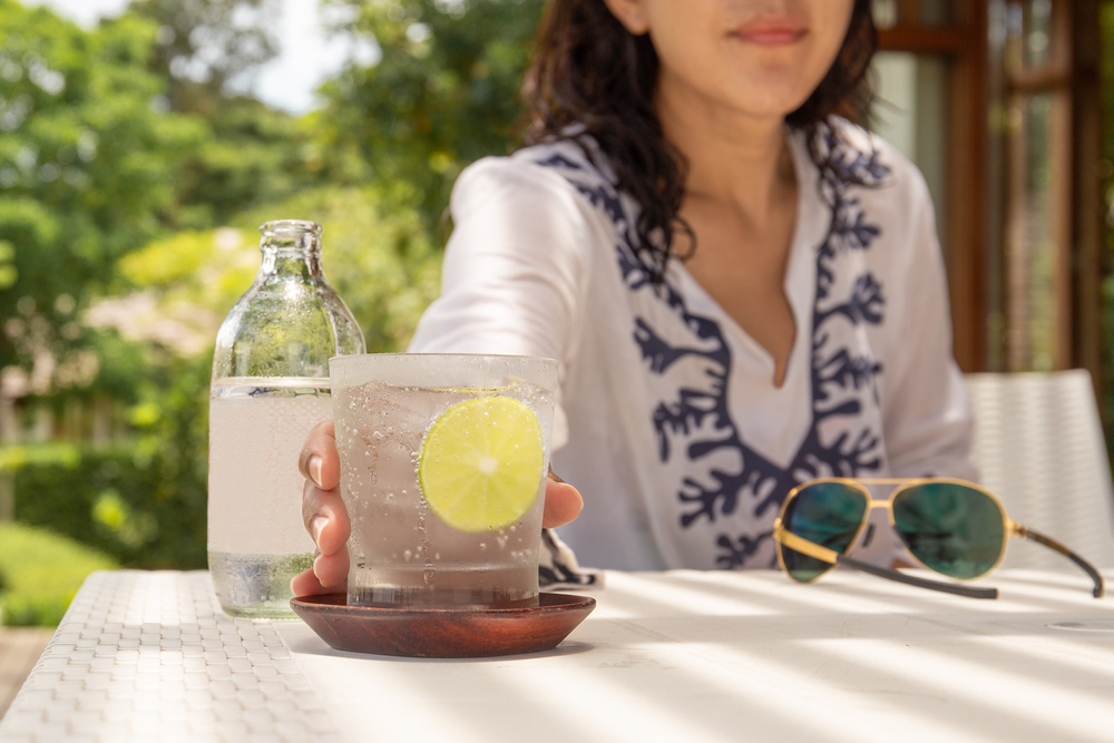 Woman hand reaching glass of healthy nutrition of sparkling water