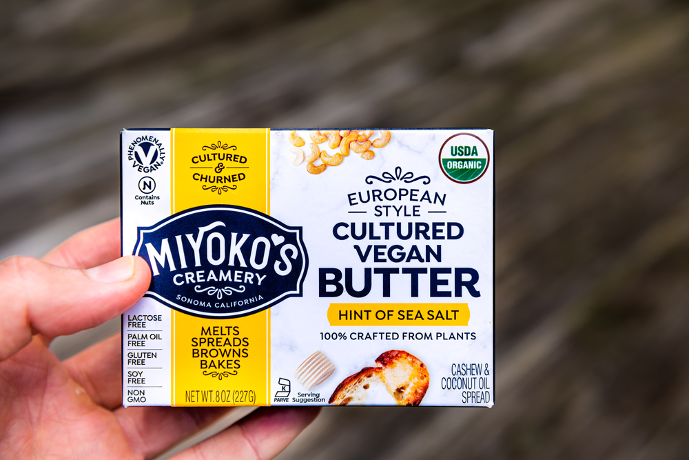 Herndon, USA - September 4, 2020: Closeup of hand holding vegan food packaged Miyoko's salted European style butter in package with sign text for creamery company
