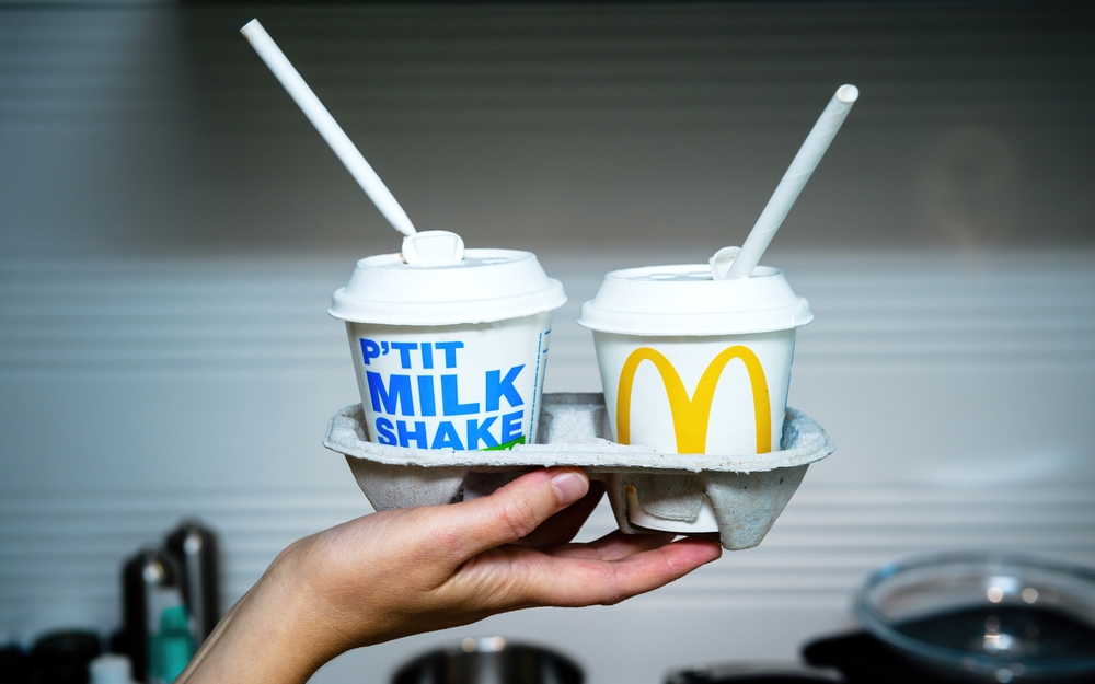 Paris, France - Aug 20, 2021: POV woman female hand holding two Milk shake in modern kitchen background manufactured by McDonald's fast food chain