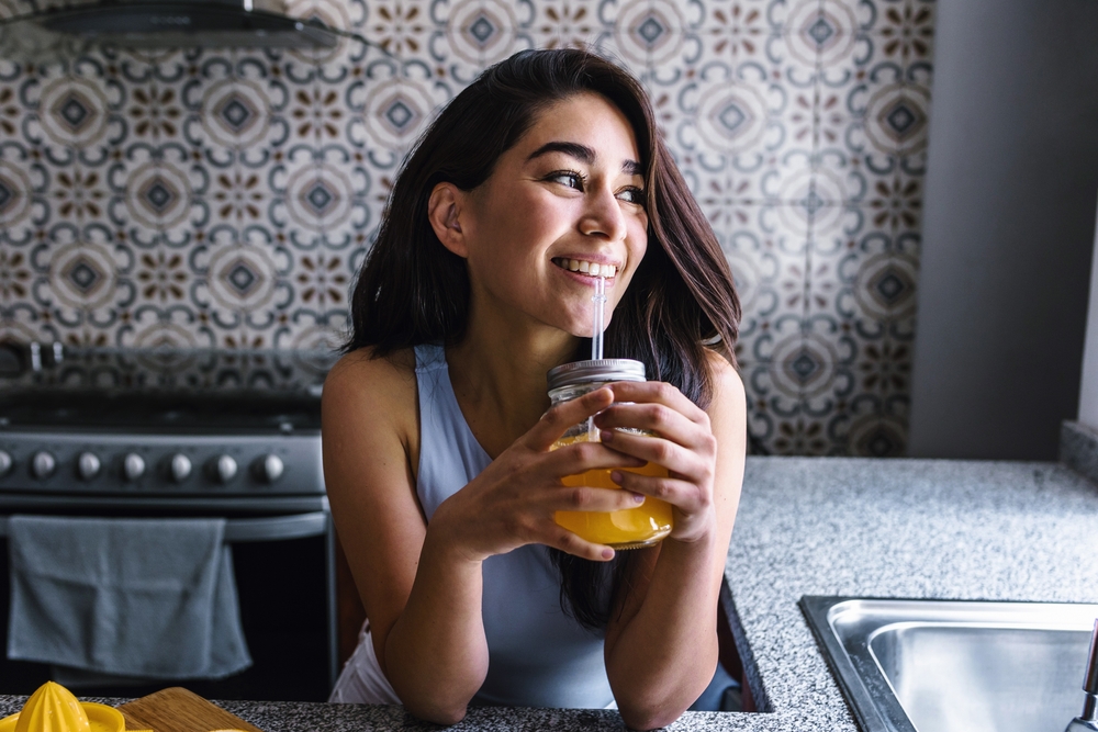 Hispanic brunette young latin woman drinking orange juice at the kitchen in Mexico Latin America

