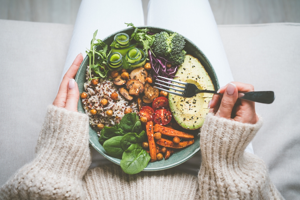 Woman holding plate with tasty vegan or vegetarian food. Healthy vegan meal. Vegan buddha bowl with healthy food. Healthy eating or diet