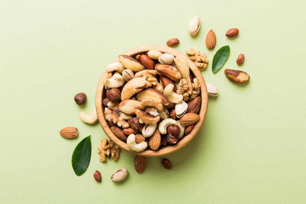mixed nuts in bowl. Mix of various nuts on colored background. pistachios, cashews, walnuts, hazelnuts, peanuts and brazil nuts.