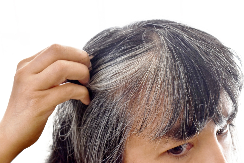Asian lady with gray hair.  Older woman with grey hair problem. Girl being stressed with damaged silver gray hair appearing on her head.