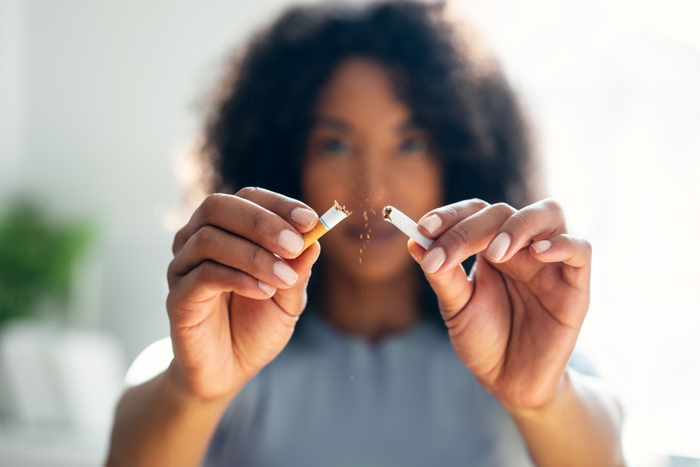 Close-up of woman breaking down cigarette to pieces. Quit smoking concept
