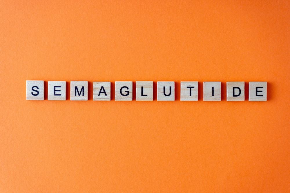 Word semaglutide. The phrase is laid out in wooden letters top view. Orange flat lay background