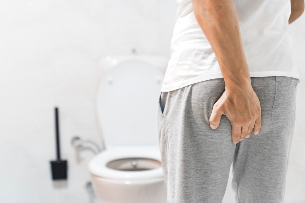 Man suffering from hemorrhoid in rest room, man has diarrhea holding his butt in toilet, diarrhea constipation. Men have diarrhea and are looking for shit.	