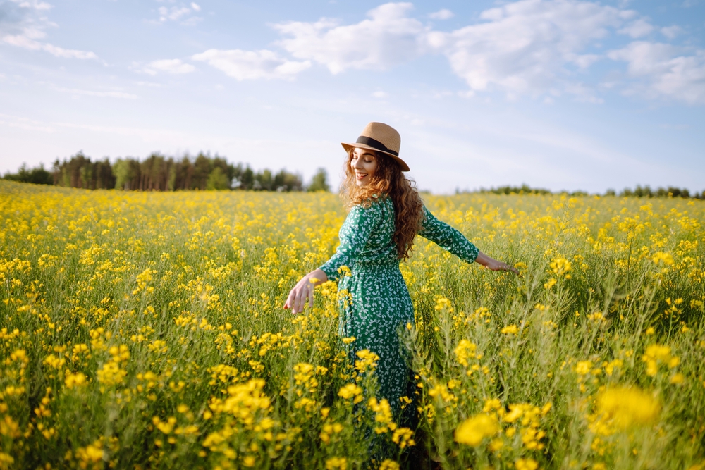 Happy woman walking in flowering field. Fashion, beauty concept. Summer landscape.