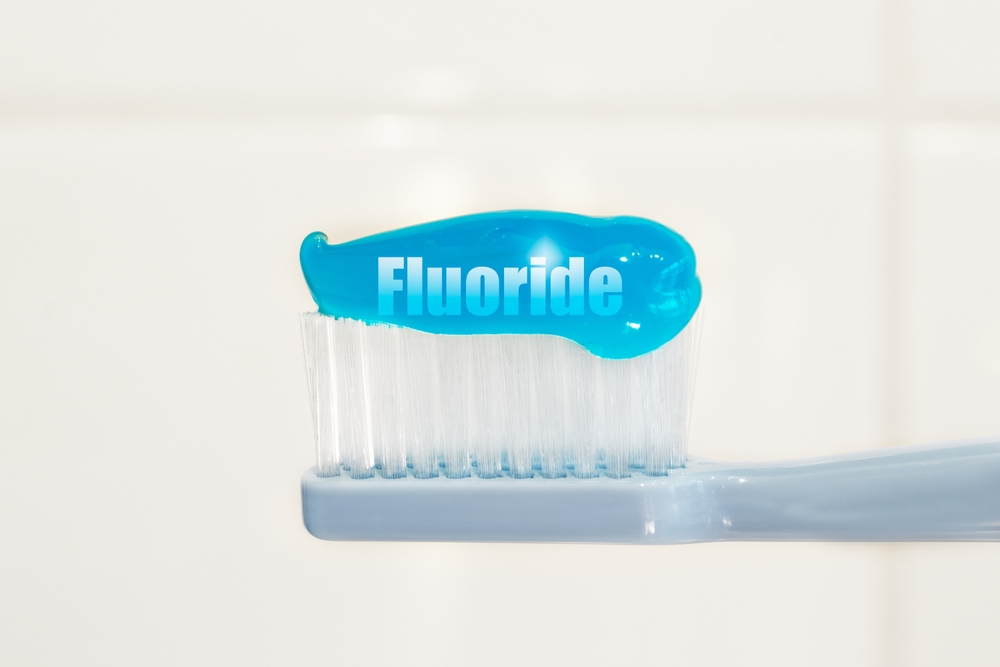  Toothbrush and fluoridated toothpaste on white background