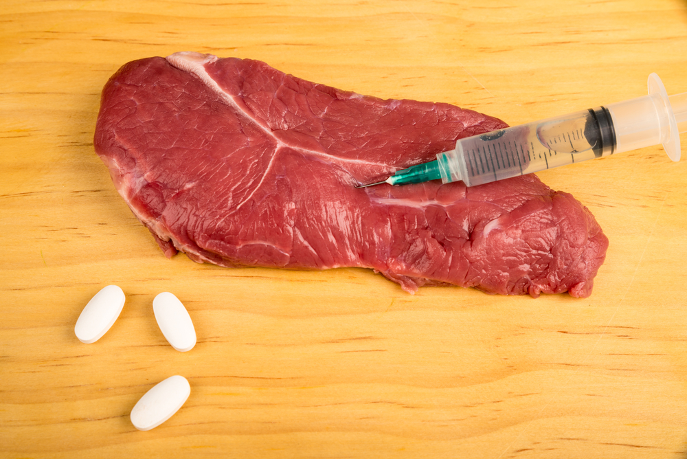 Hormones being injected in a beef steak, a conceptual food manipulation shot