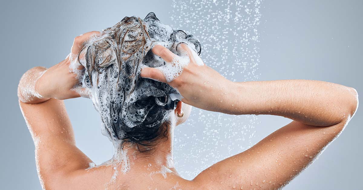 woman seen from behind washing her hair in a shower