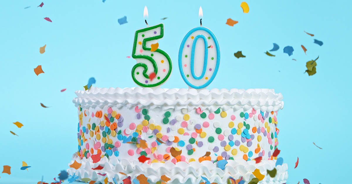 Birthday cake with white icing and sprinkles with number fifty candles. Turning 50 concept