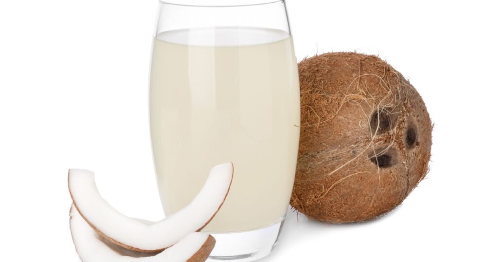 Glass of coconut water and nuts isolated on white