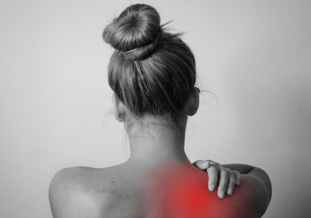 woman reaching back towards pain in her shoulder