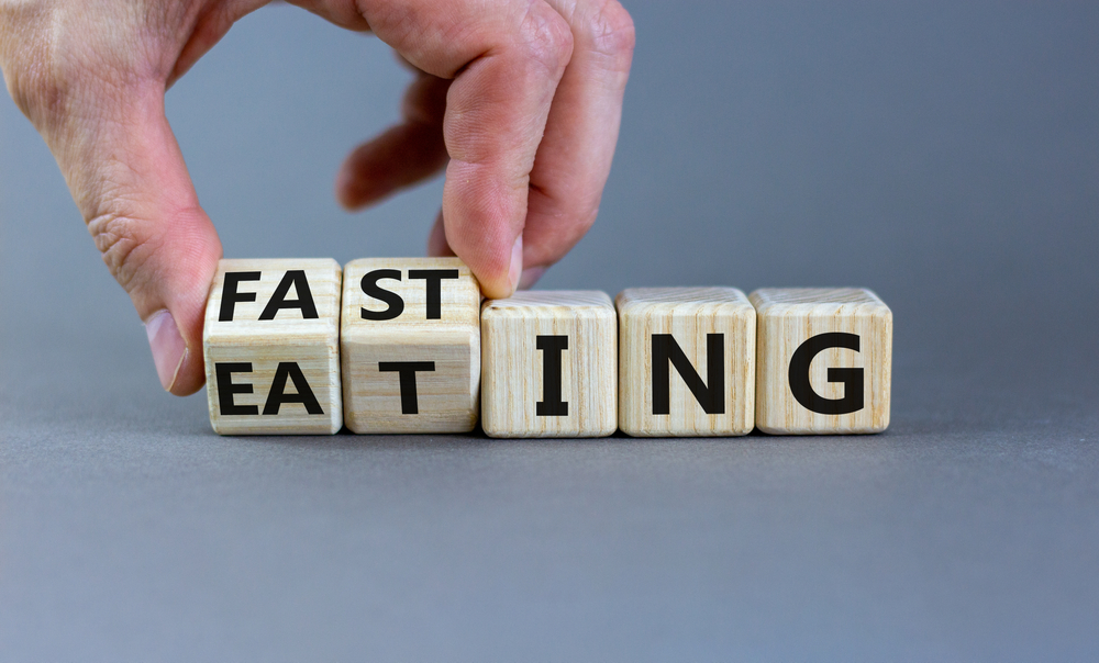 Fasting or eating symbol. Doctor turns wooden cubes and changes the word 'eating' to 'fasting'. Beautiful grey background, copy space. Healthy eating, medical and time to fasting concept.