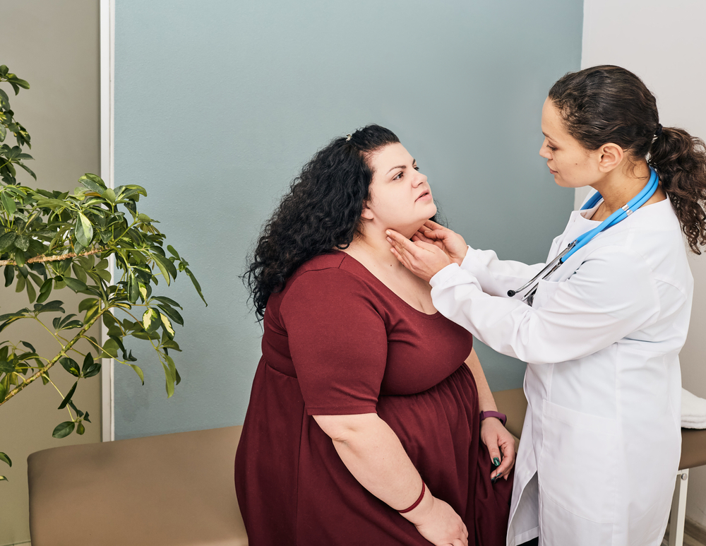 Doctor palpation of fat woman's neck for diagnostics of thyroid diseases and hypothyroidism.
