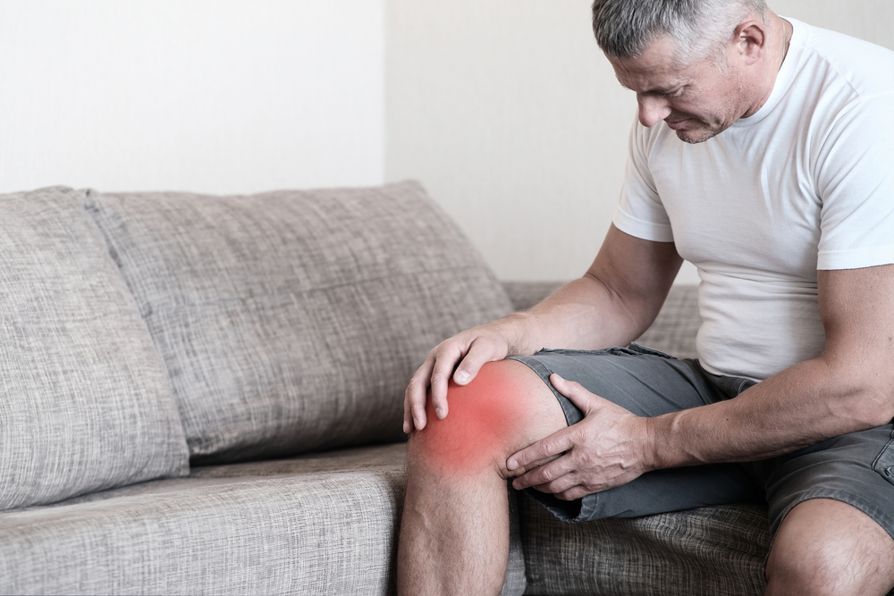 Arthritis is a disease of the joints.A man on a couch, squeezing his knee from excruciating pain
