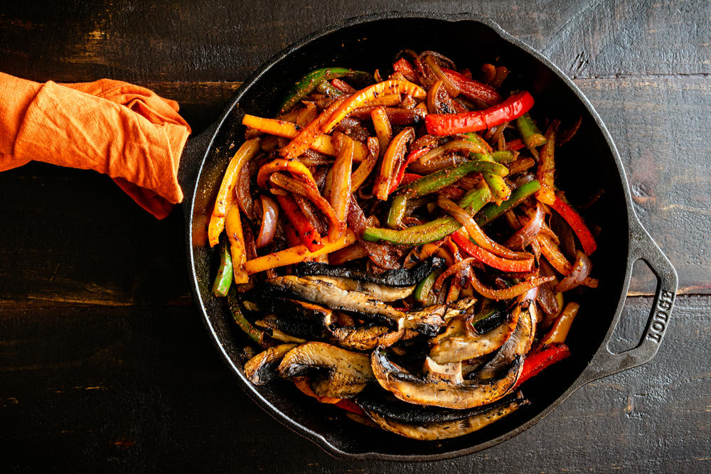 Vegan Fajita Filling in a Cast Iron Skillet: Charred bell peppers, red onion, and portobello mushrooms mixed with spices

