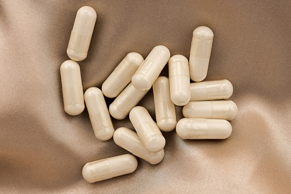 n-acetyl cysteine (NAC) supplement capsules on silk background. mental wellbeing and personal health concept
