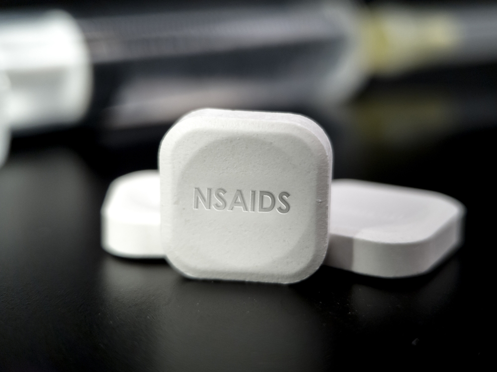 Tablet of NSAID drug medication on black background. Nonsteroidal anti-inflammatory drug is medication used to reduce pain, decrease inflammation and fever and prevent blooc clots

