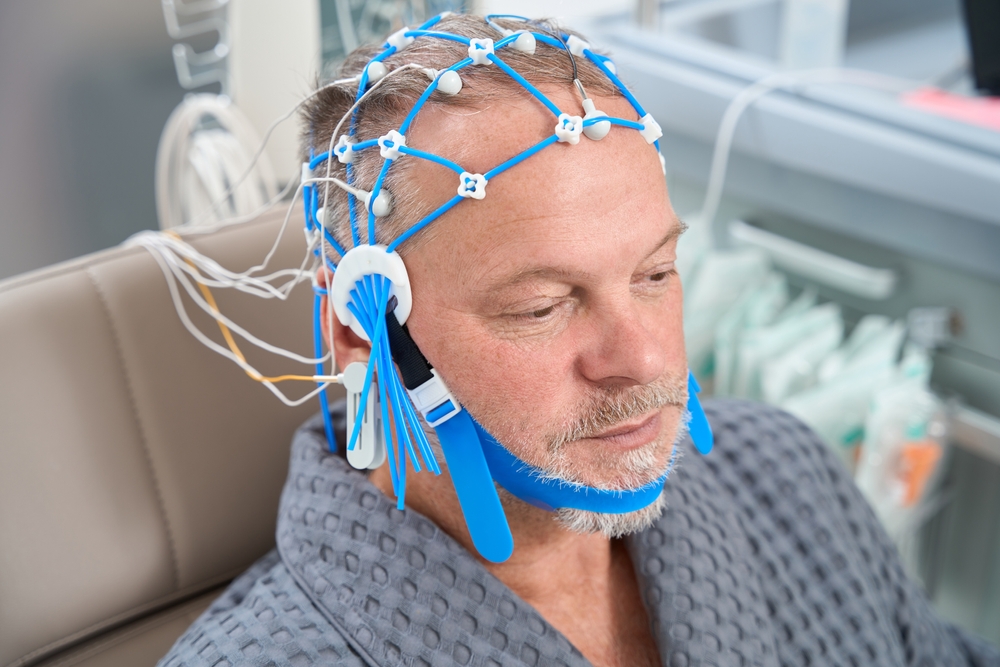 Man has cap of electrodes for encephalography on his head