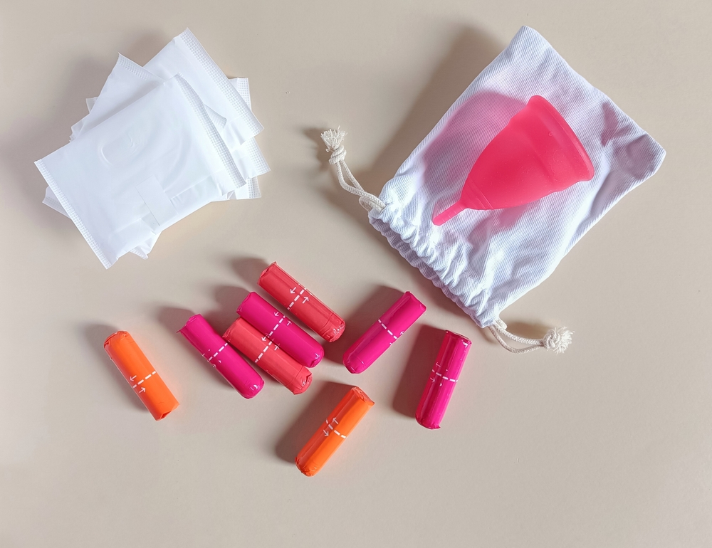 The concept of intimate female care. Pads, colorful sanitary tampons, menstrual cup on a light background. Soft selective focus
