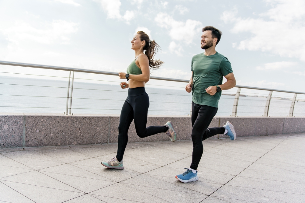 A group of friends exercises for cardio endurance, use a fitness watch and an app. Runners athletes in fitness clothes. Beautiful jogging in sports shoes. Motivation for a healthy lifestyle.
