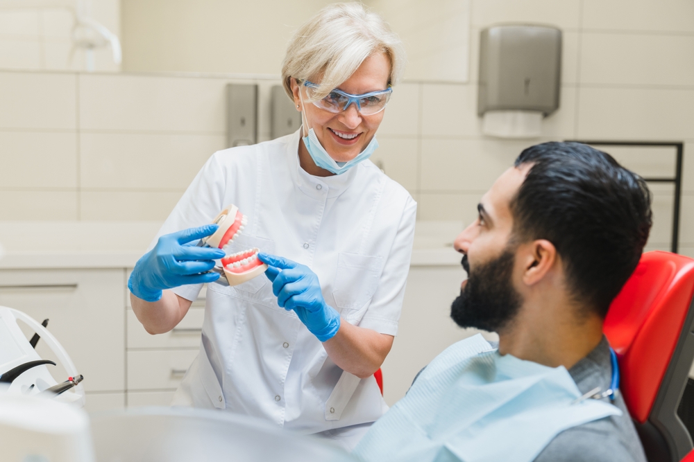 Caucasian stomatologist female dentist orthodontist showing explaining teeth tooth problems diagnosis on dental jaws miniature

