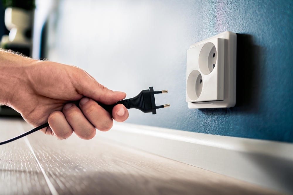 Socket, plug and electric power outlet. Man unplugging or holding cable wire cord in hand. Save energy. Electricity from home wall. Electrical current conservation. Insert adapter or charger.
