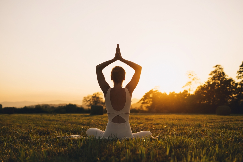 Young woman practicing yoga on nature. Girl meditating outdoors. Female with slim, strength and flexibility body. Healthy lifestyles. Concept of vitality, calmness, relax, mindfulness, zen energy.
