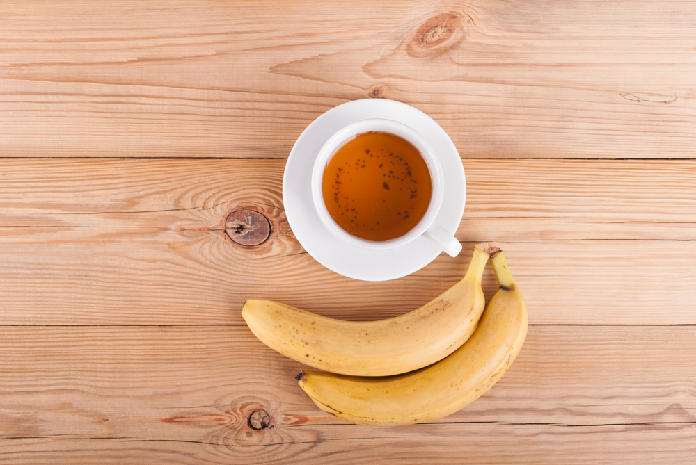 Tea and bananas on a wooden table. View from above .
