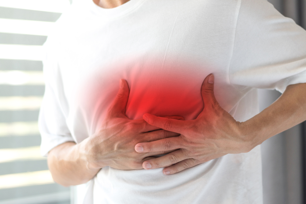 Man's hands on his chest in white shirt with red spot as suffering on chest pain. Male suffer from heart attack,Lung Problems,Myocarditis, heart burn,Pneumonia or lung abscess, pulmonary embolism day
