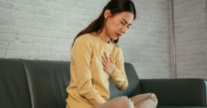 woman placing hand on chest experiencing heartburn symptoms