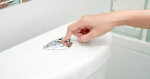 9 Reasons For Smelly Urine - and What To Do person using push button flush on toilet